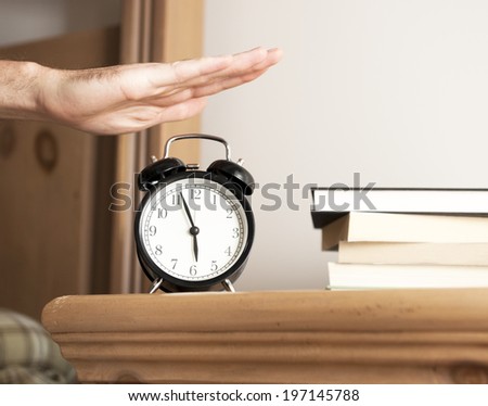 A hand prepares to turn off the bedside alarm clock.