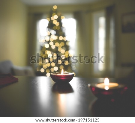 A living room at Christmas with a tree and burning candles.