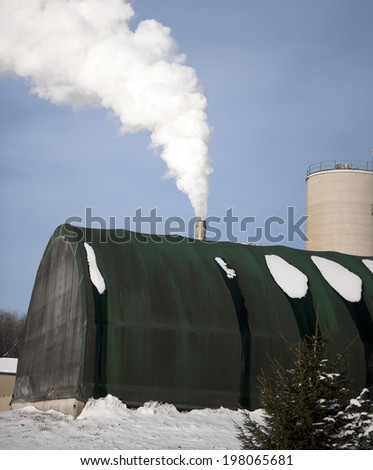 A rounded building with a smoke stack and snow on the ground.