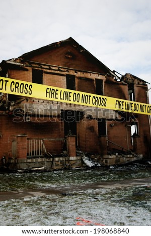 A fire damaged brick building with a yellow fire tape sealing it off.