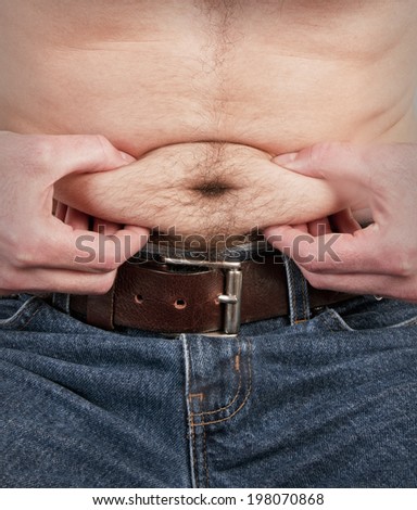 A man squeezing his belly fat around his belly button.
