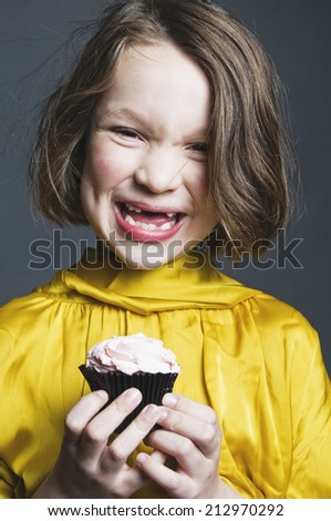 Smiling gap-toothed girl with cupcake