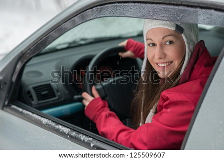 Woman driving in winter on snow covered slippery road in forest
