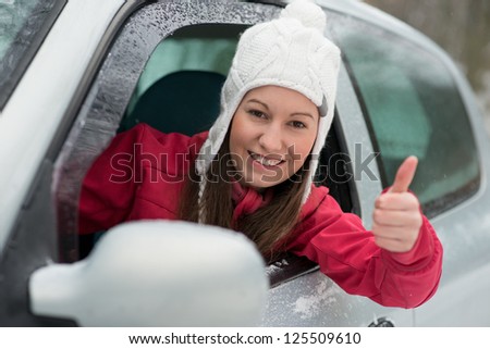 Woman driving in winter on snow covered slippery road in forest