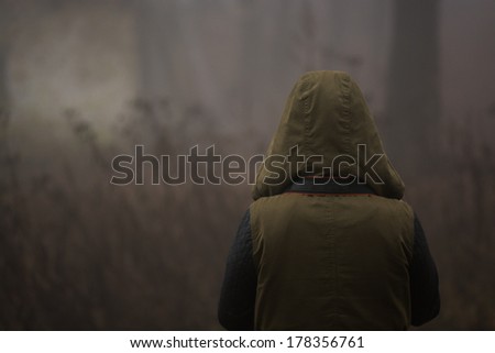 strange person walking in a dark foggy forest