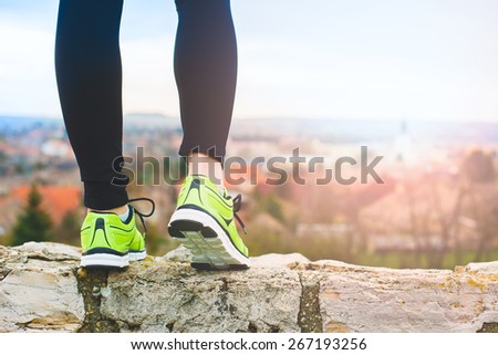 Runner feet running on the top of a hill closeup on shoe. woman fitness sunrise jog workout wellness concept.