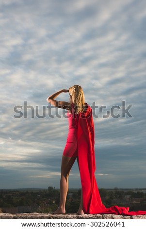 Young woman posing as superhero over the city