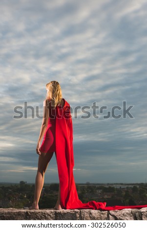 Young woman posing as superhero over the city