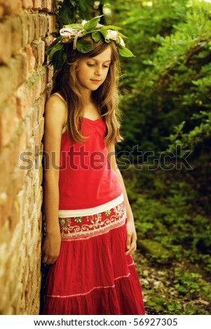 Young girl with rose wreath on head stand on park