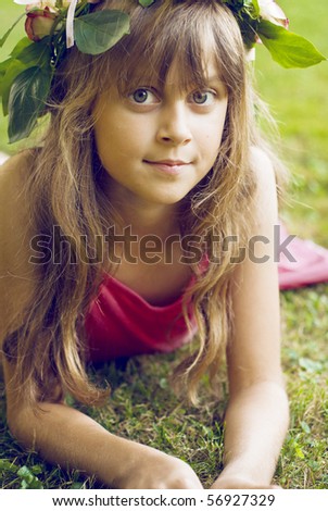 Young girl with rose wreath on head stand on park