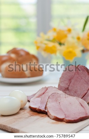 Ham on Easter table with eggs, flowers and decoration
