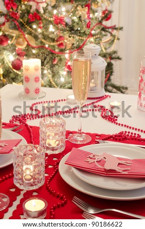 A decorated christmas dining table with champagne glasses and christmas tree in background