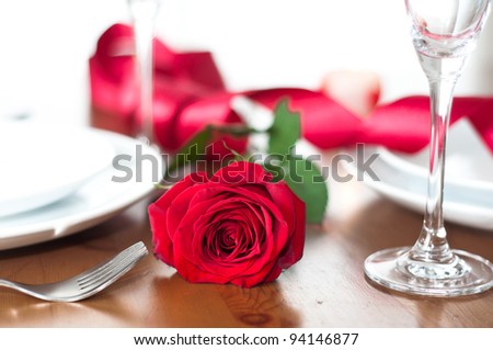 Romantic dinner setting with a rose and champagne glasses