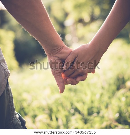 Young couple in love walking in the summer park holding hands, filtered image