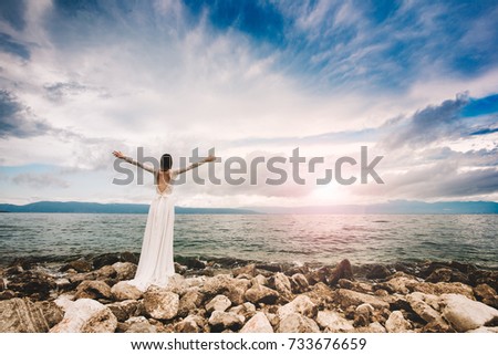 Wedding at the beach. Island wedding. Beautiful bride standing with open arms.  Relaxed woman enjoying sun, freedom and life an beautiful beach in sunset. Young lady feeling free, relaxed and happy.