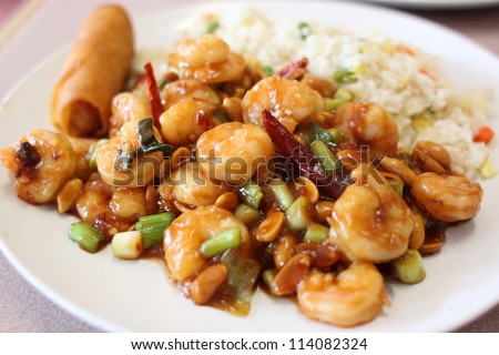 Plate of kung pao shrimp with rice and egg roll at a Chinese restaurant.
