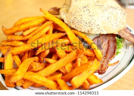 Delicious gourmet hamburger served with sweet potato French fries at a restaurant.