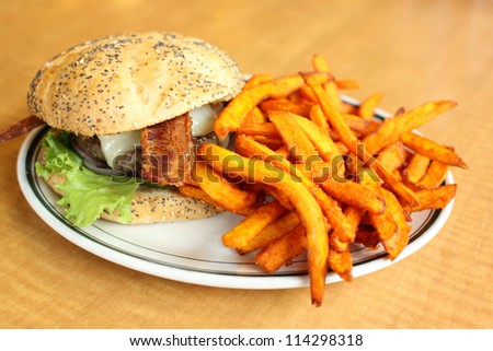 Delicious gourmet hamburger served with sweet potato French fries at a restaurant.