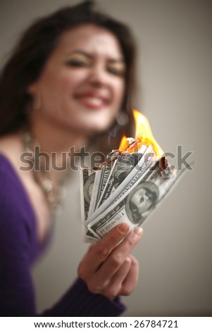 A young and attractive woman burning money.