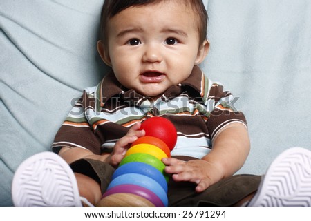 Happy toddler with colorful toy sitting on light blue sofa.