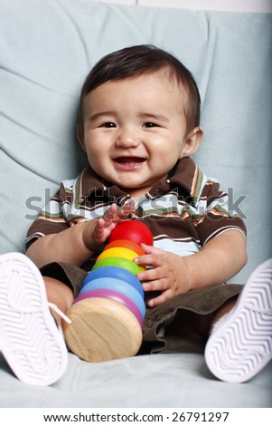 Smiling toddler with colorful toy sitting on light blue sofa.