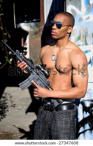 A fit young man with an assault gun.