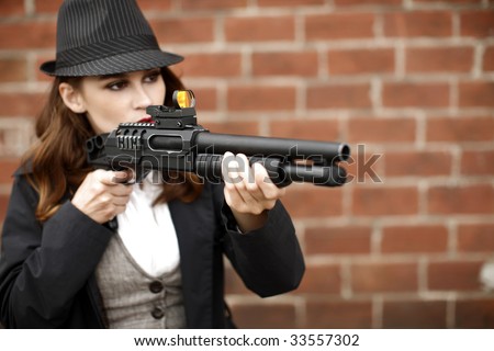 A young and stylish woman pointing a shotgun.