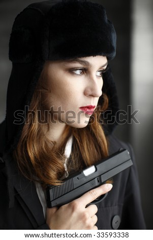 A young and stylish woman holding a pistol safely with her finger off the trigger.