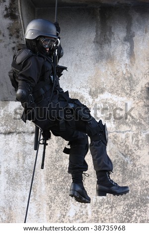 Officer in full tactical gear with weapons climbing down a rope.