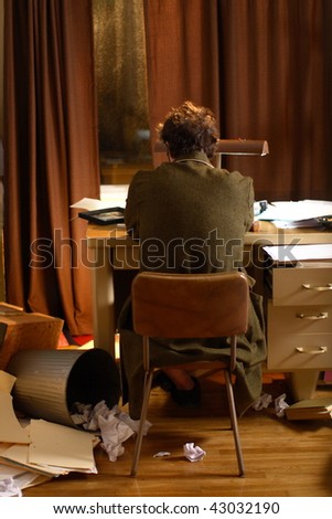 Man sitting at his desk in a messy apartment.