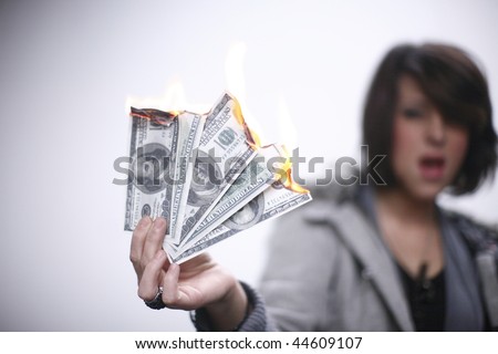 Young and sexy woman burning hundred dollar bills.
