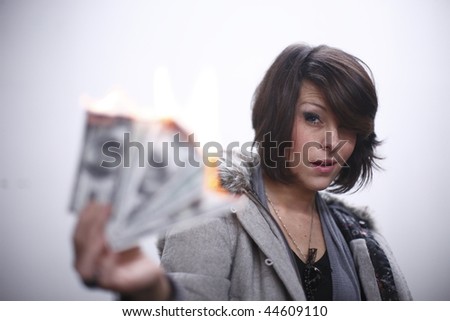 Young and sexy woman burning hundred dollar bills.