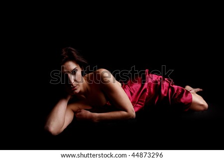 Beautiful woman covered in red satin sheet.