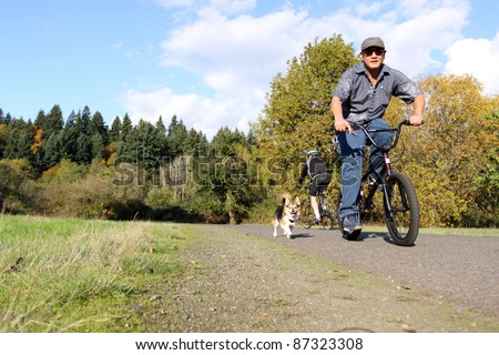 Asian man riding bicycle with pet dog.