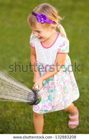 Little girl playing with a water sprayer