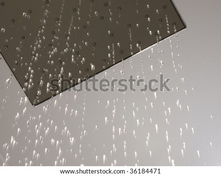 Detailed shot of a shower-head with shower spray. Water droplets are frozen.