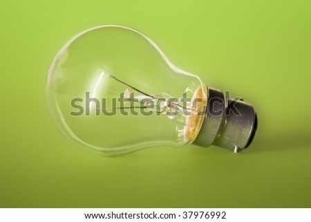 A lit light bulb on green background.