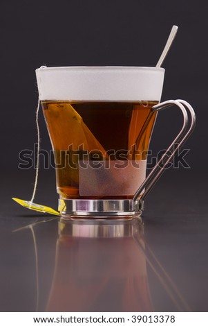 Transparent cup of black tea with teabag and tag