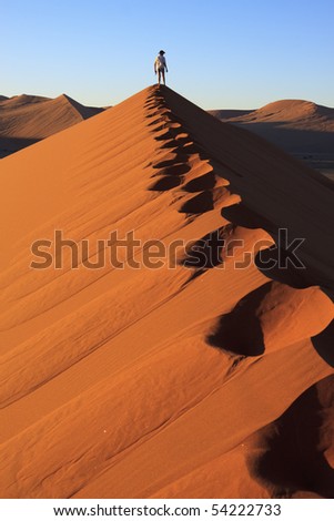 Footprints and man looking at the view at the top of a dune
