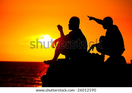 silhouette of two man talking at sunset