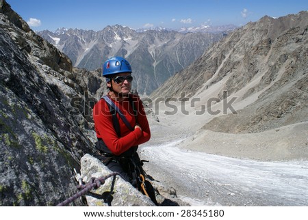 Climber in red clothes stands on a background mountains
