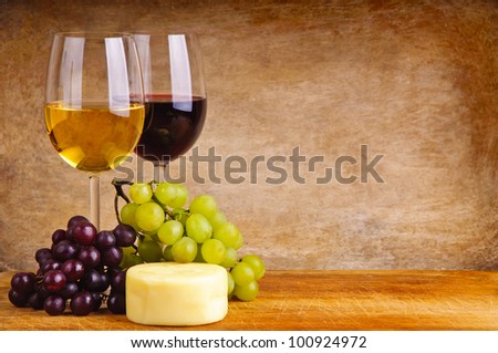 glass of red and white wine, cheese and grapes on a wooden background
