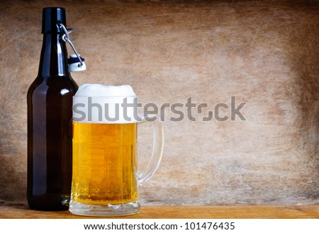 beer bottle and mug on a vintage wooden background with text copy space
