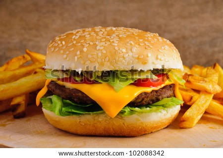 Cheeseburger with french fries on a wooden plate