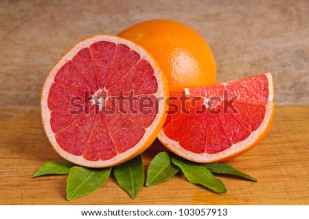 fresh pink grapefruit and leaves on a wooden background