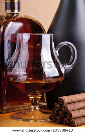 glass and bottle of brandy with cigarillos
