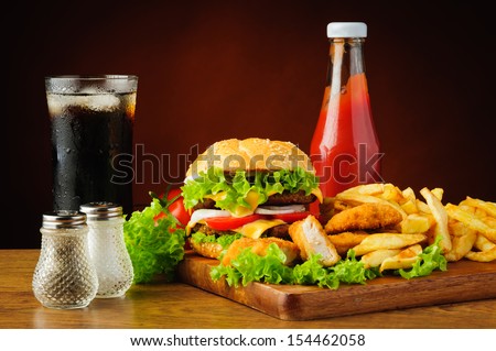 still life with hamburger, chicken nuggets, french fries, cola drink and tomato ketchup