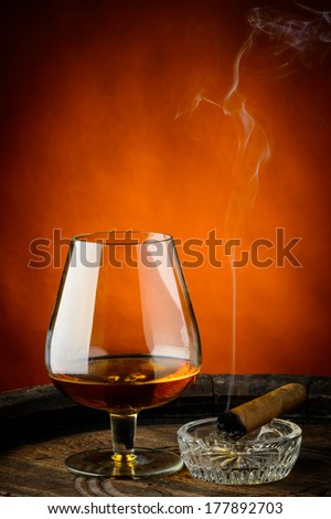still life with glass of cognac and cigar on a wooden barrel
