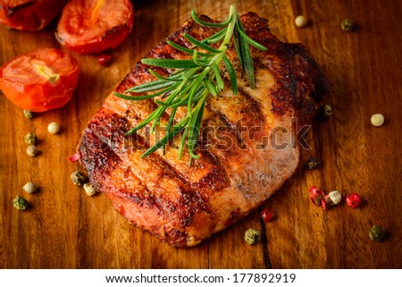 closeup detail of grilled meat steak with spices and rosemary on a wooden plate