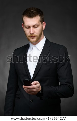 young business man looking at phone over a dark background
